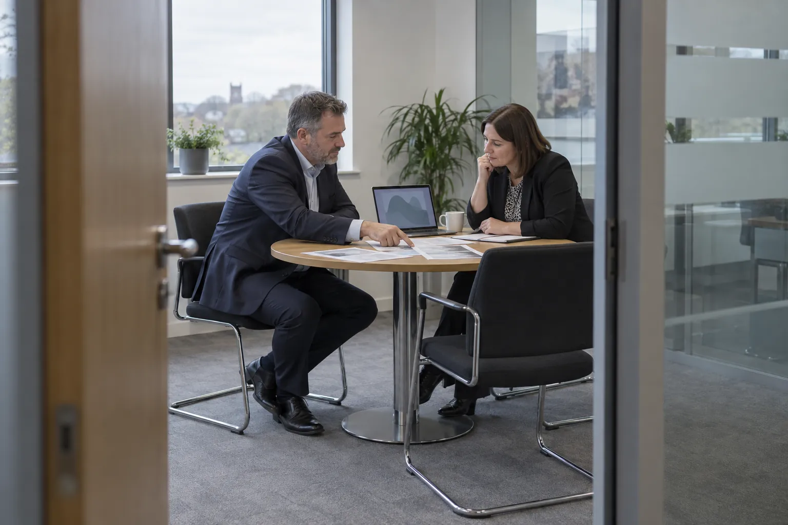 A facilities manager and a cleaning contract manager reviewing an agreement at a meeting table.