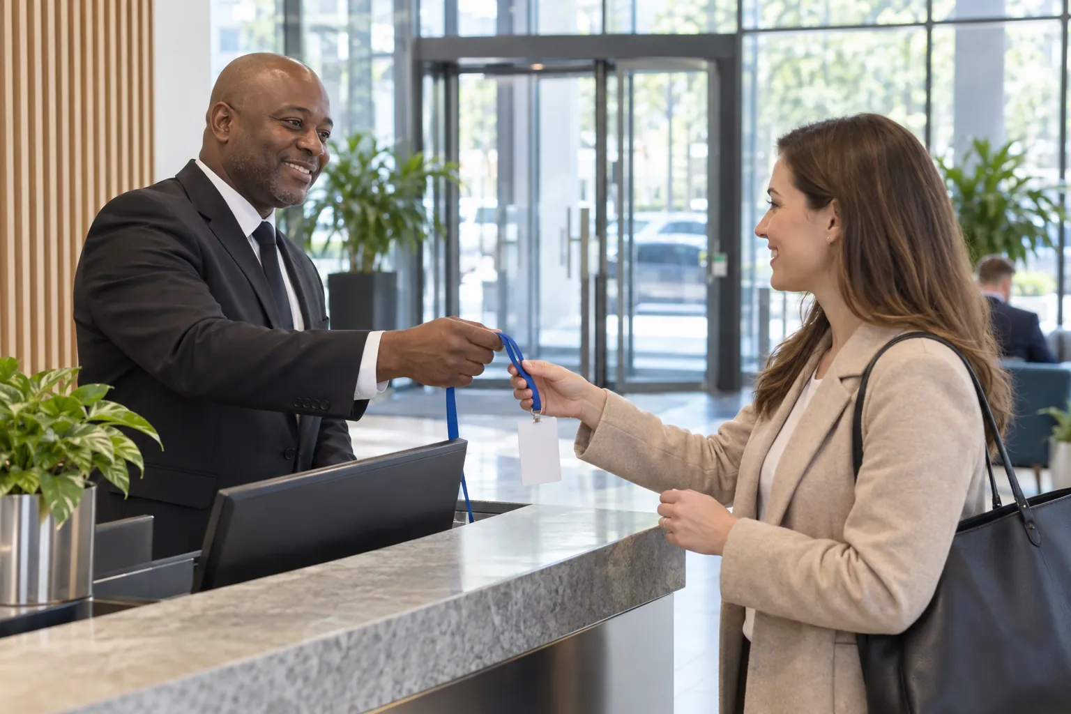 A security officer at an office reception desk handing a visitor pass to a visitor.